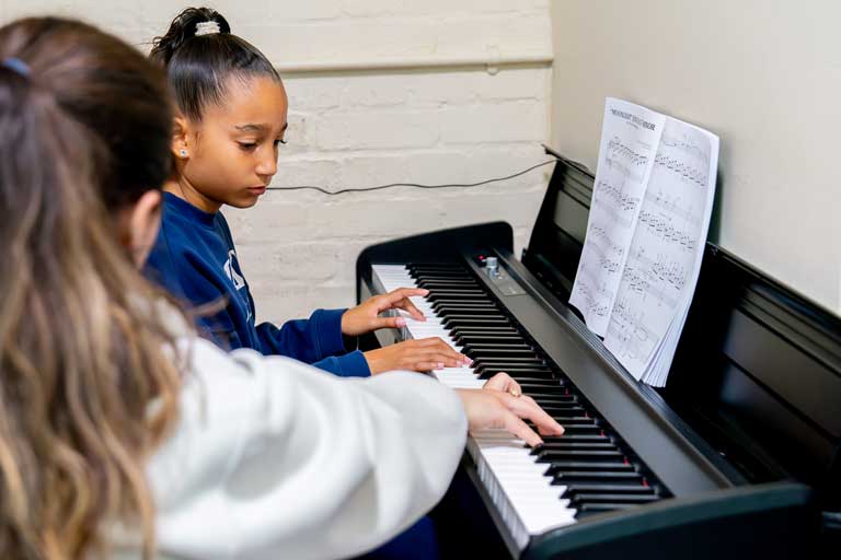 A school student concentrating during a piano lesson provided by The Dan Tien